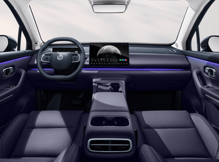 Innenraum eines Autos mit modernem Design. Lenkrad links, großes digitales Display in der Mitte des Armaturenbretts, das ein Bild eines Planeten zeigt. Dunkelviolette Sitze und Mittelkonsole, Armaturenbrett mit lila LED-Leuchten. Große Fenster bieten viel Licht.